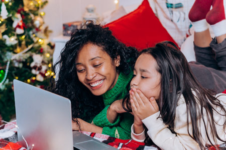 Brunette daughter and black mother chat using laptopの写真素材