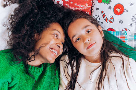 Mother and daughter lie and laugh on Christmas pillowsの写真素材