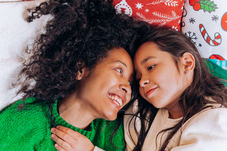Mother and daughter lie and laugh on Christmas pillowsの写真素材