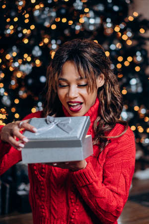 Young curly woman gets surprised with Christmas presentの写真素材