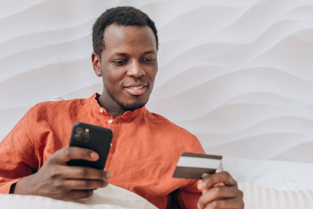 African-American man pays online with phone and credit cardの写真素材