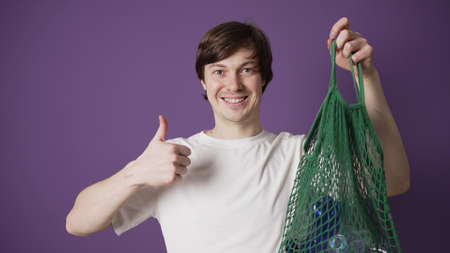 Young man encourages people to recycle plastic bottlesの写真素材