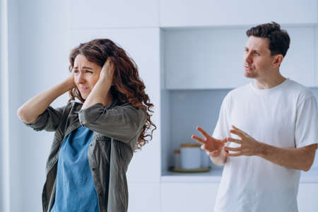 Family conflict, the husband yells at his wife standing at the window with her ears closedの写真素材