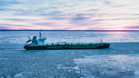 Cargo ship sailing through cold ocean water with broken iceの写真素材