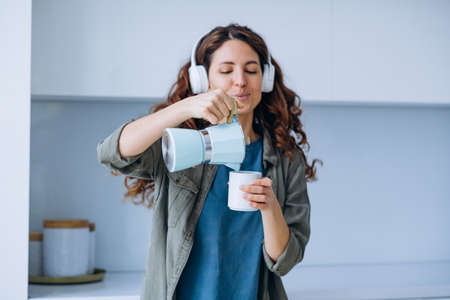 Woman dances to music in headphones with coffee in cupの写真素材
