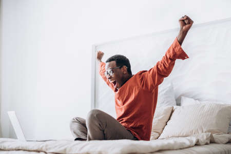 African-American guy puts hands up sitting near laptopの写真素材