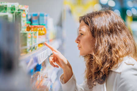 woman reads the composition on baby juice in a supermarketの写真素材