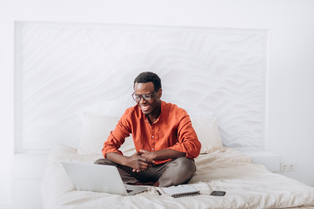African-American man freelancer works on laptop on bedの写真素材