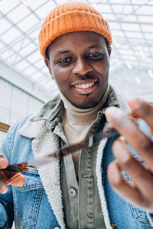 Smiling African-American man looks at photos on film in roomの写真素材