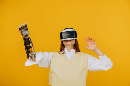 Woman in vest with bionic arm and VR headset plays gameの写真素材