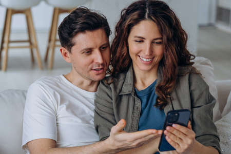 Young husband and wife discuss photos from social mediaの写真素材