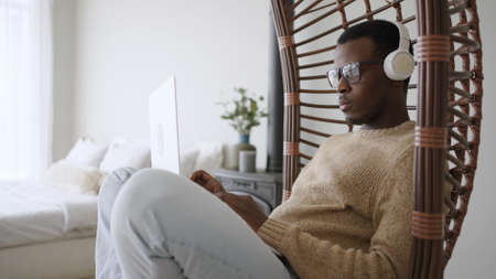 Young student listens to educational audio in swinging chairの写真素材