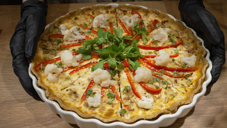 Female hands in rubber gloves put vegetable pie on table