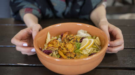 Woman with manicure taps fingers on bowl of shrimp saladの写真素材