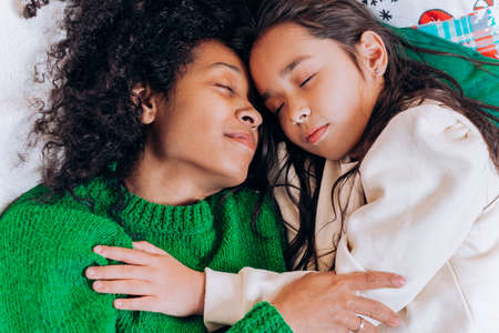 Mother and daughter lie and laugh on Christmas pillowsの写真素材