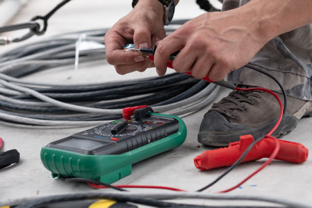 Close-up of an electrical engineers hand ringing a cable with a multimeter or measuring voltage at a...