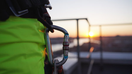 Climber on rooftop attaches carabiner to loop on equipmentの写真素材