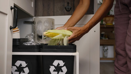 Woman peels off corn throwing outer leaves into trash binの写真素材