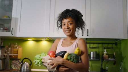 African American woman holds paper bag with fresh vegetables