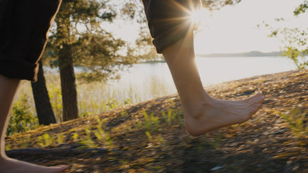 Legs of man walking on forest path near river closeupの写真素材