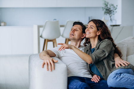 Happy Couple Relaxing on Sofa in Modern Living Room, Sharing a Joyful Momentの写真素材