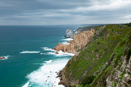 Rugged Cliffs Overlooking the Atlantic Ocean with Waves Crashing Against the Shoreの写真素材
