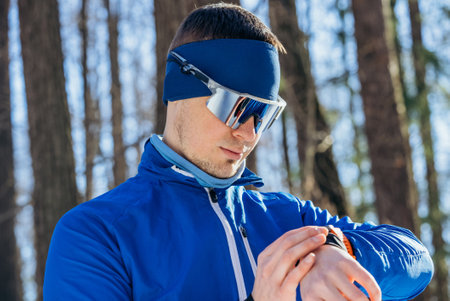 Skier in Blue Checking Smartwatch GPS During Winter Trainingの写真素材
