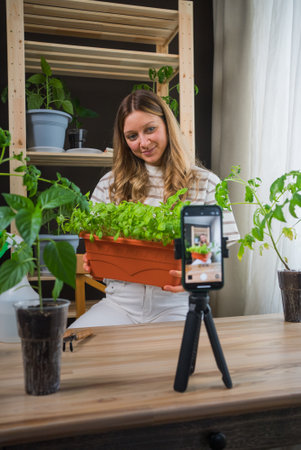 Woman Filming Indoor Gardening Tutorial with Potted Herbsの写真素材