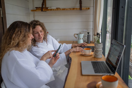 Girls working at laptops at same table distracted by conversation, interesting information, gossip