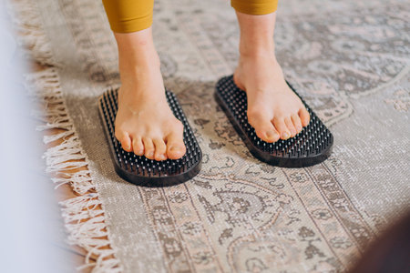 Close-up of woman standing on acupressure massage mats, focusing on foot therapy and relaxation.