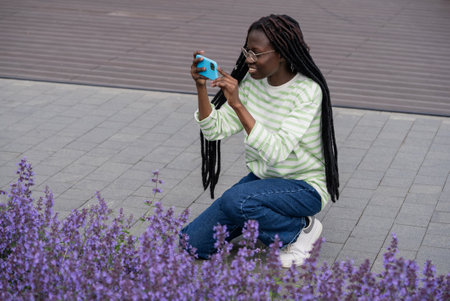 Young woman with dreadlocks takes photo of lavender in parkの写真素材