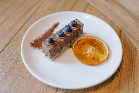 Chocolate Mousse Cake with Blueberries and Dried Orange Slice on White Plateの写真素材