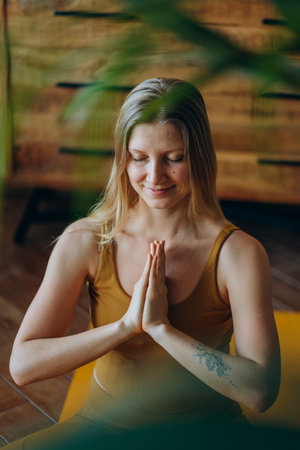 Woman Meditating with Hands in Prayer Pose Indoorsの写真素材