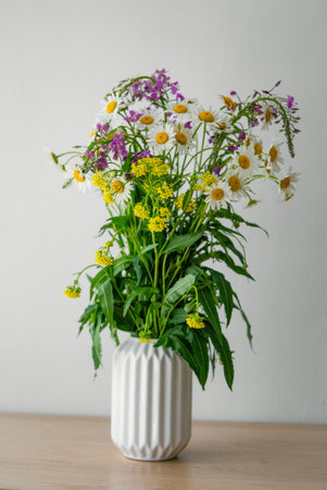 Wildflower Bouquet in a White Ceramic Vase on Wooden Tableの写真素材