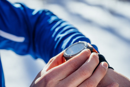 Close-up of athlete checking smart watch during winter trainingの写真素材