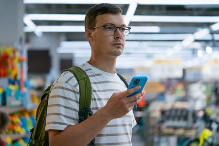Man using smartphone while shopping in a grocery storeの写真素材