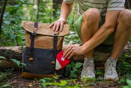 Hiker packing first aid kit into backpack during outdoor adventureの写真素材