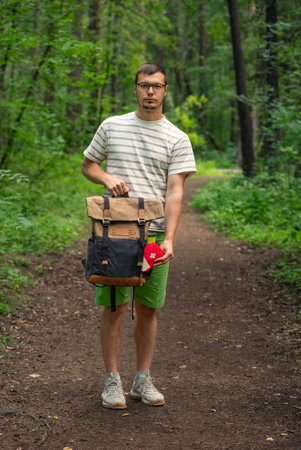Hiker holding a first aid kit in a lush forest, enjoying the outdoors on a sunny day. His backpack suggests an active lifestyleの写真素材