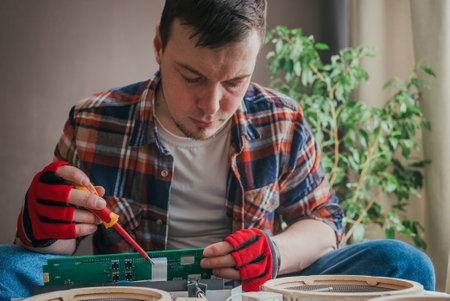 Experienced electrician repairs circuit board with precision and focus, showcasing expertise in electronics industry. Close-up shot in workshopの写真素材