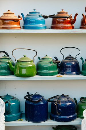 Collection of vintage enamel teapots on shelves. Assorted colorful kitchenware in rustic style.の写真素材