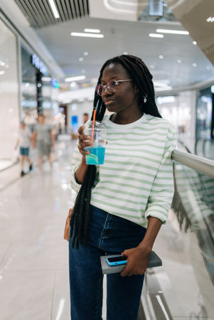 Young woman holding blue slush drink inside shopping mallの写真素材