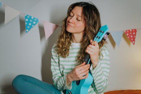 Young woman playing ukulele at home with party garland decoration