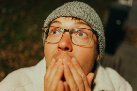 Shocked man wearing glasses and beanie looking up in amazementの写真素材