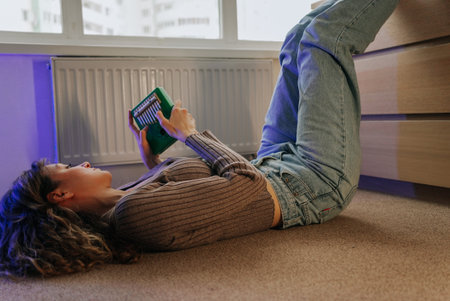 Woman playing kalimba laying on floor at homeの写真素材