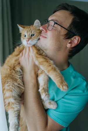 Man holding and cuddling a ginger catの写真素材