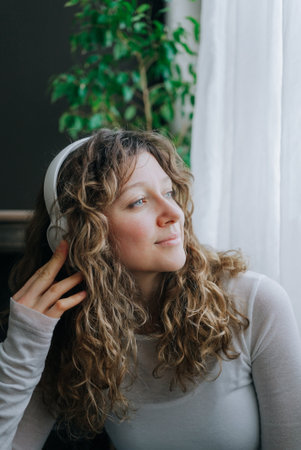 Young woman listening music with headphones and looking out windowの写真素材