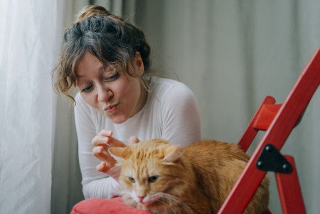 Woman making funny face while petting ginger catの写真素材