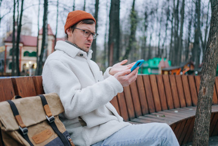 Confused freelancer receiving bad news while working remotely in parkの写真素材