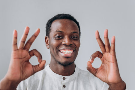 Cheerful young man showing ok sign with both handsの写真素材