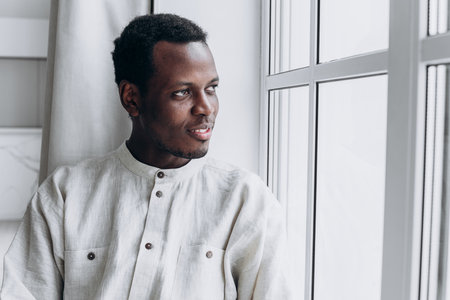 Young black man wearing casual clothing looking out windowの写真素材